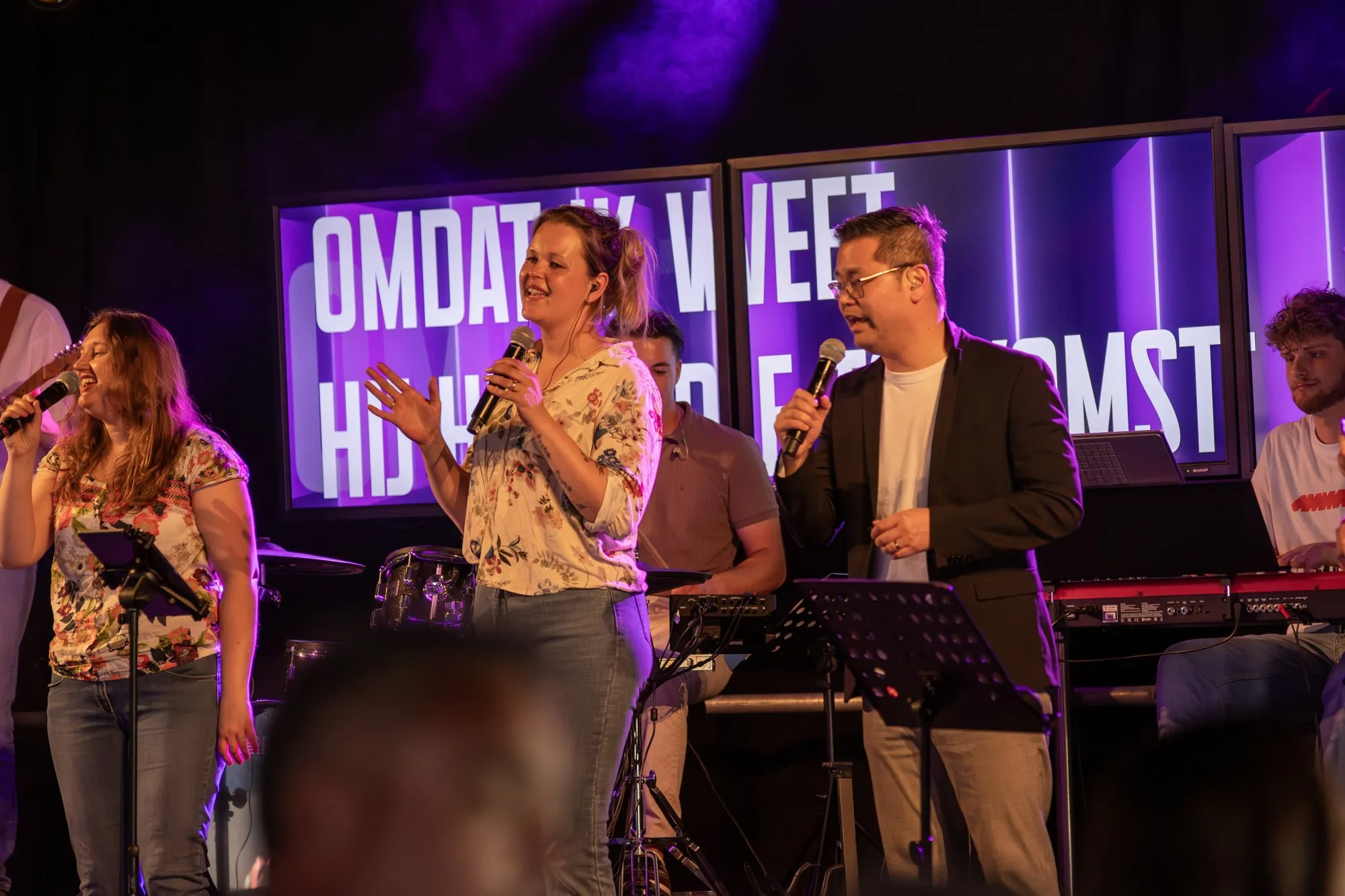 Zangers van de Samen Praise Band onder paars podiumlicht